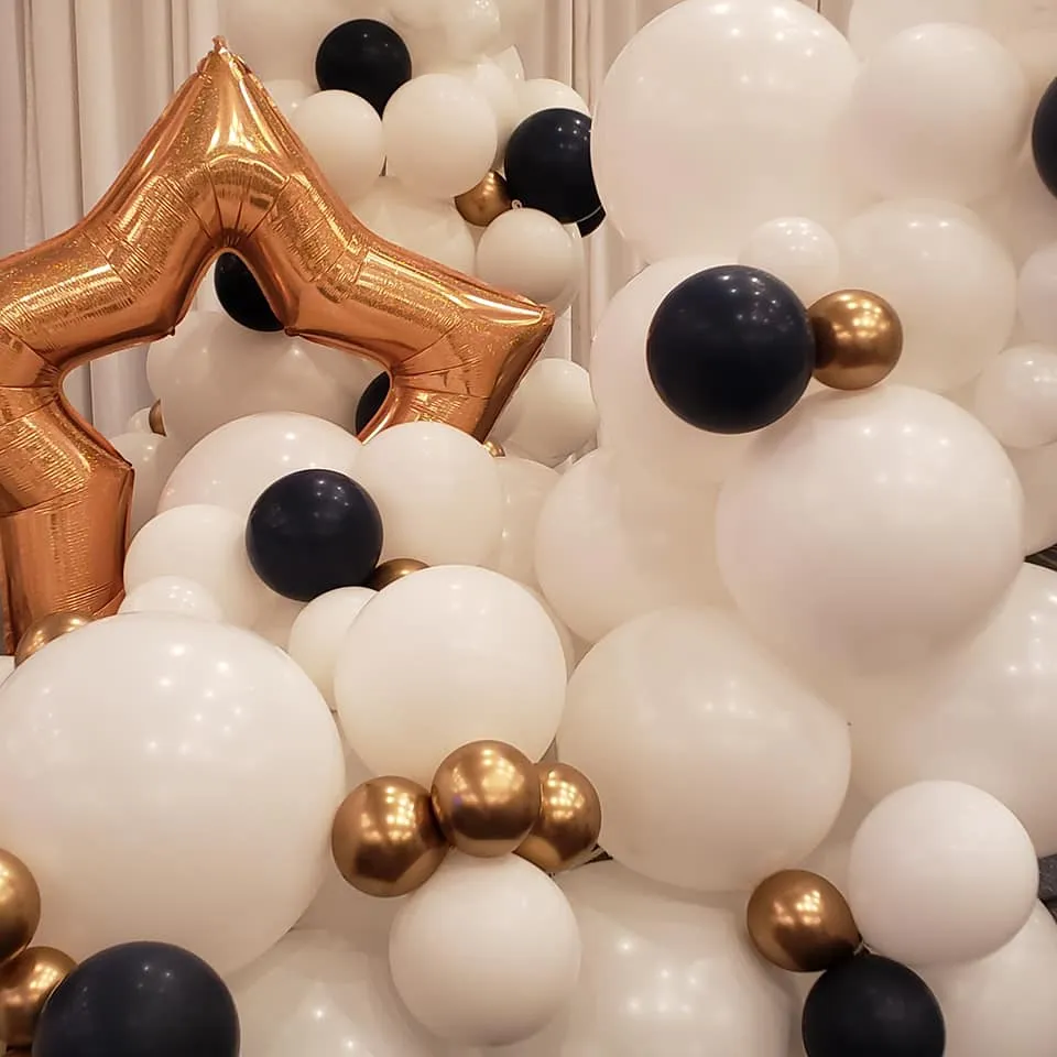 white, black, and gold balloon wall with a foil star balloon