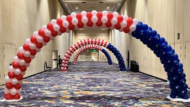 red, white, and blue balloon arches in a hallway