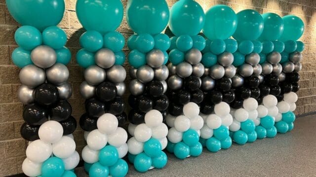 Eight balloon columns that are turquoise, silver, black, and white