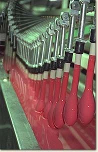 Balloon dipping industrial line. Balloon molds emerging from vat of red latex.